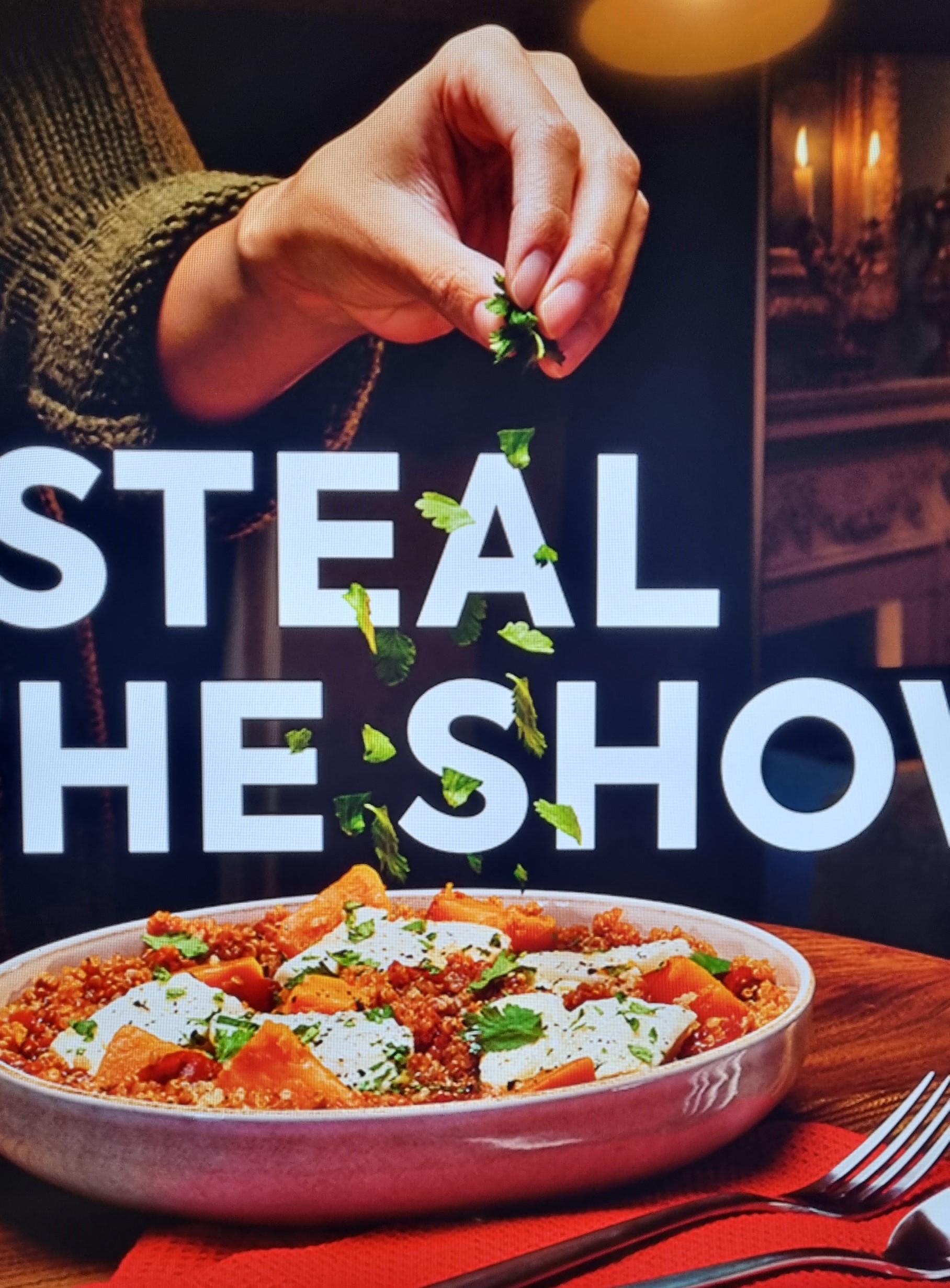 A photo of the TV ad showing a hand sprinkling coriander leaves over a dish, with two lines of text placed in amongst the individual leaves to give a layered effect.